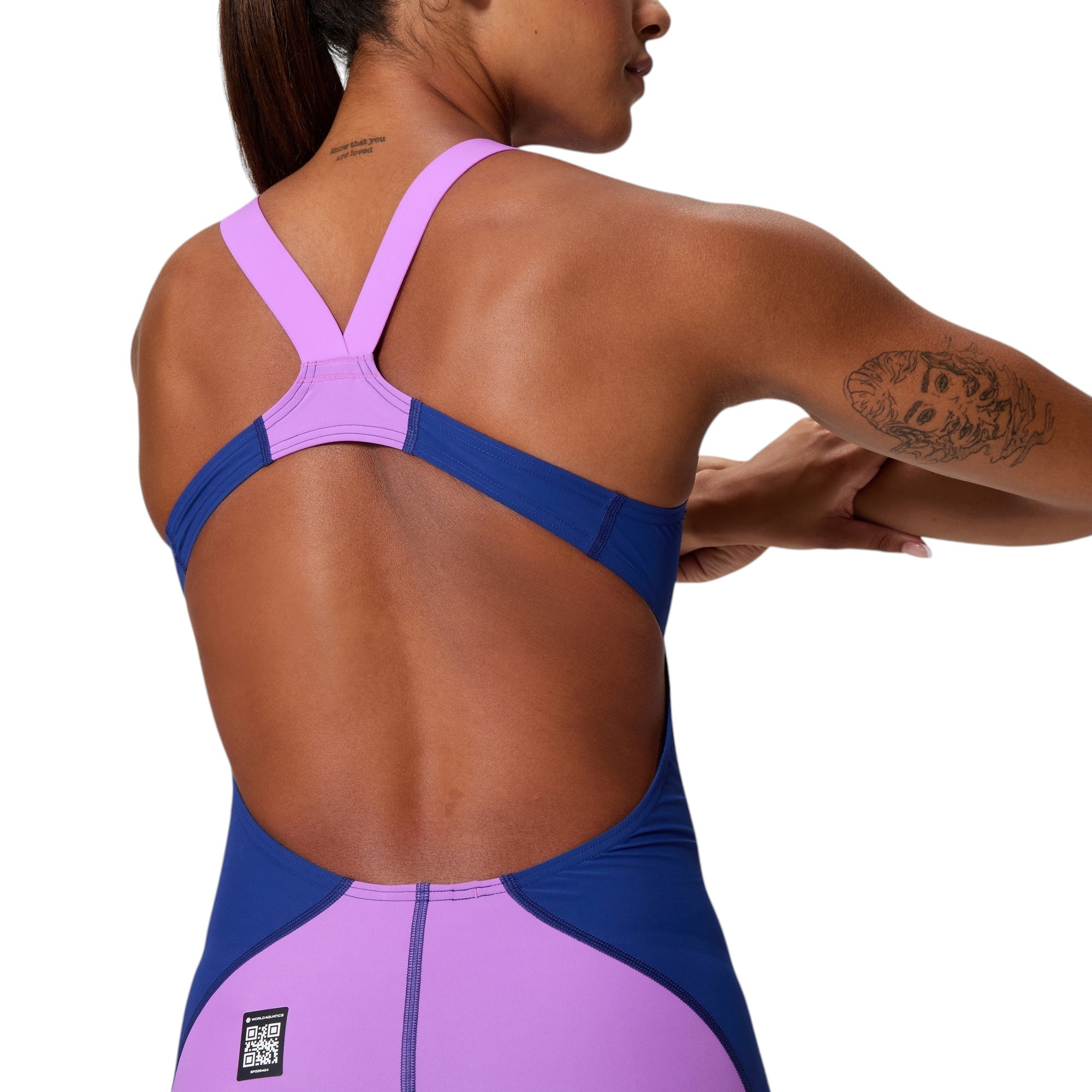Speedo LZR Pro 2.0: Close-up of open-back. Highlights lavender V-straps and Navy side panels on a model. Includes World Aquatics QR logo.