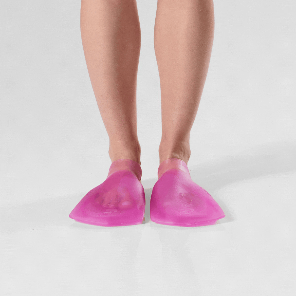 Rotating image of all 4 angles (front, both sides, and back) of a person standing while wearing translucent deep pink FINIS SlipFin Pro swim fins against a white background.