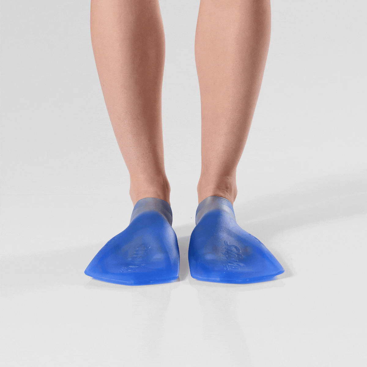 Rotating image of all 4 angles (front, both sides, and back) of a person standing while wearing translucent marine blue FINIS SlipFin Pro swim fins against a white background.