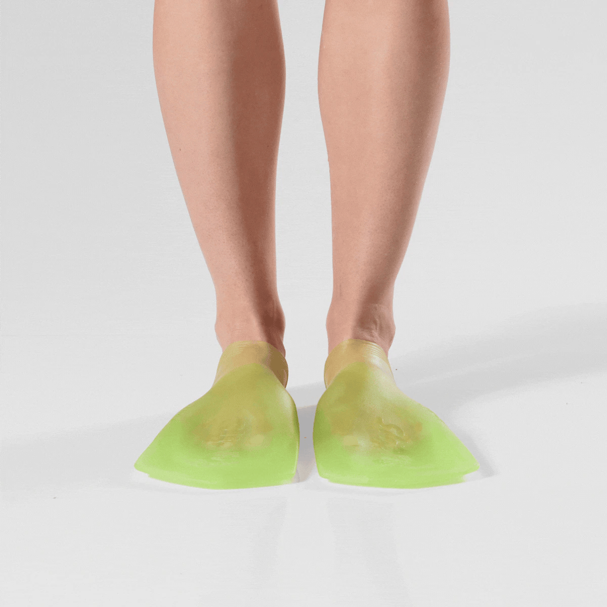 Rotating image of all 4 angles (front, both sides, and back) of a person standing while wearing translucent volt green FINIS SlipFin Pro swim fins against a white background.